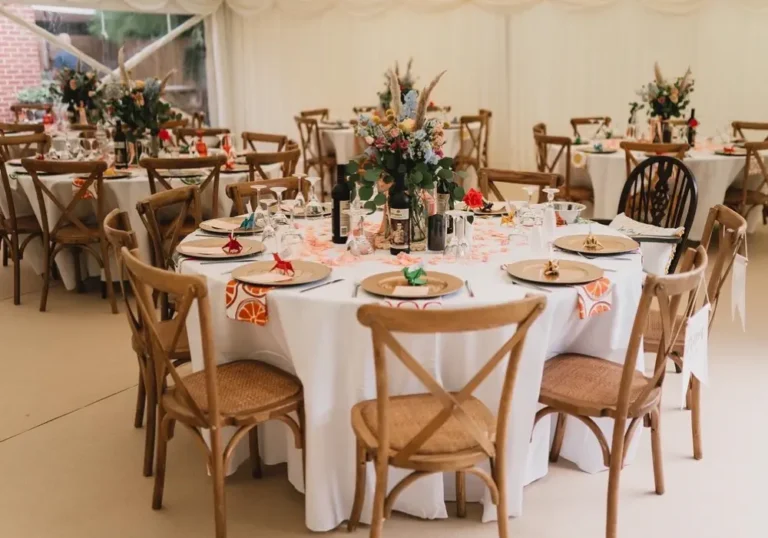 Elegant dining setup for an event with round tables, floral centerpieces, and wooden chairs in a Melody Corporation marquee.
