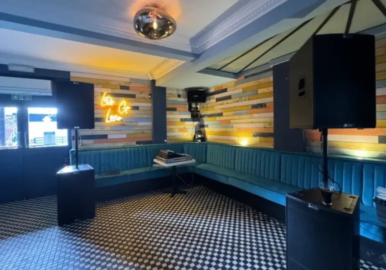A cozy bar area with patterned floor tiles, booth seating along the walls, a disco ball, PA systems by Melody Corporation.