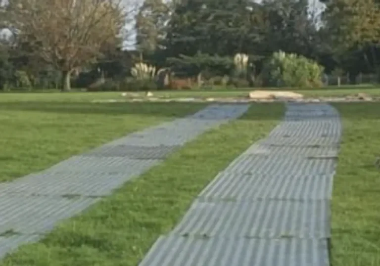 Portable trackway grid panels laid over grass in a park for marquee use by melody corporation.
